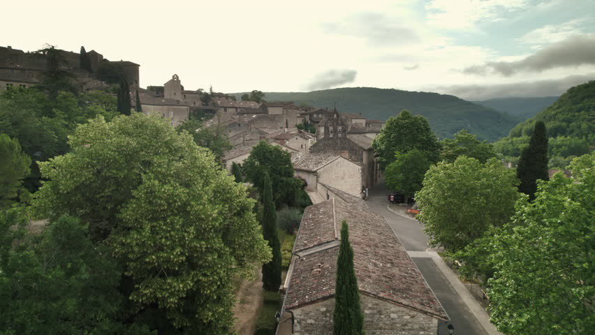 Aerial shot of the town of Bruniquel in the south of France. French village on a hill in the middle of the forest with a medieval castle on the edge of a cliff with a view of a river. Royalty-Free Stock Footage #1111685765