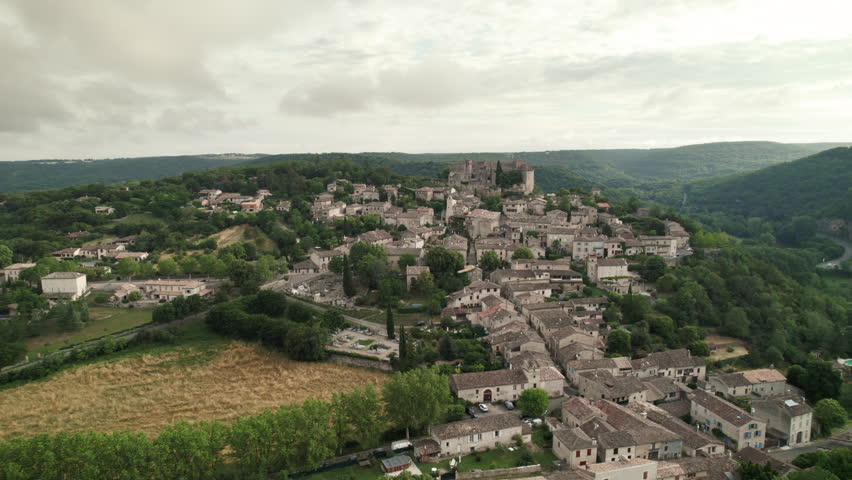 Aerial shot of the town of Bruniquel in the south of France. French village on a hill in the middle of the forest with a medieval castle on the edge of a cliff with a view of a river. Royalty-Free Stock Footage #1111685771