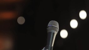 close-up of a microphone against a bokeh background. Concert microphone on stage on a dark background with bokeh. A microphone on a stand stands on the stage, blurred background with bokeh.