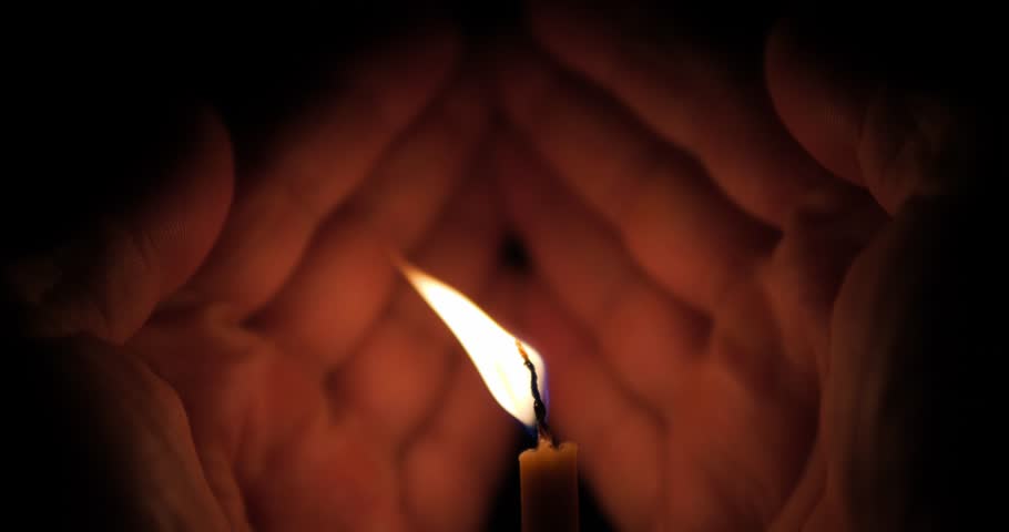 A memorial candle in the palms. The candle flame is protected from the wind with hands. A candle in the dark. | Shutterstock HD Video #1111691285