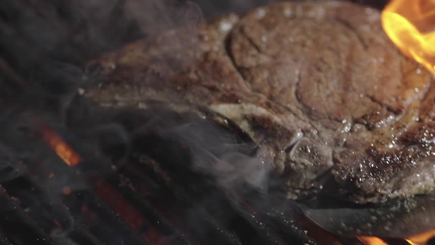 Roast beef. Beef steak on grill with flames. Rib-eye steaks cooking on flaming grill. A top sirloin steak flame broiled on a barbecue. Steak on the grill. Meat grilled on barbecue.