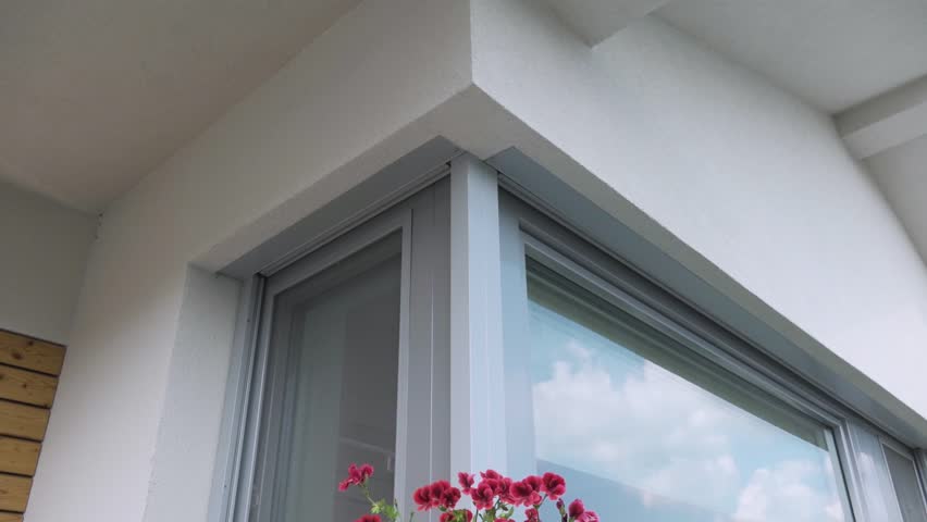 Automatic exterior blinds and curtains on the window with flowerpots and flowers