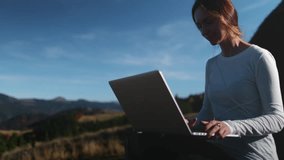 Woman working on notebook in mountain countryside landscape. Freelancer female work remotely, autumn sunset scene. Travel, freedom, active lifestyle, online digital job. Panoramic shot, slow motion - Powered by Shutterstock - Get 15% off with code: PIKWIZARD15