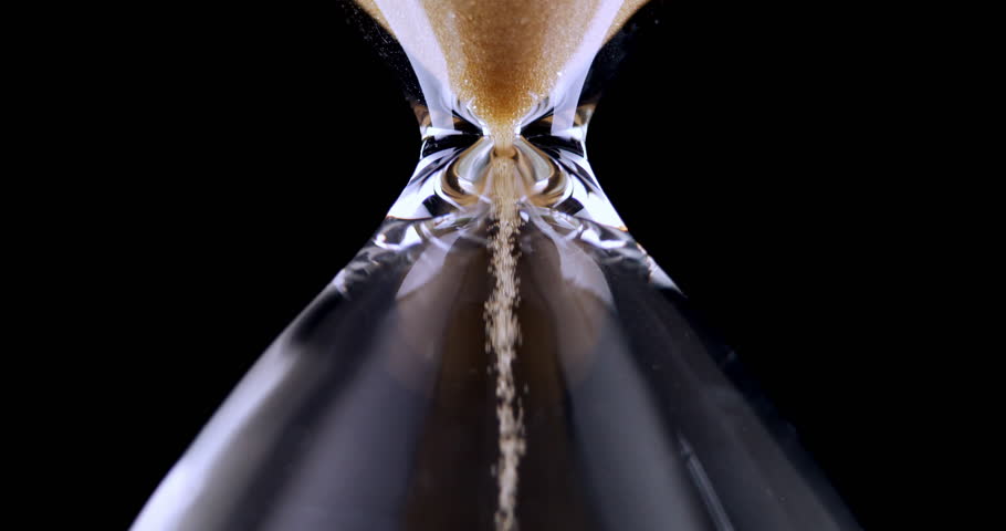Hourglass. Sands move through hour glass. Sandglass close-up on a black background. Slow motion video. A pile of Golden sand at the bottom of the hourglass, small grains of sand fall from above. | Shutterstock HD Video #1111695053