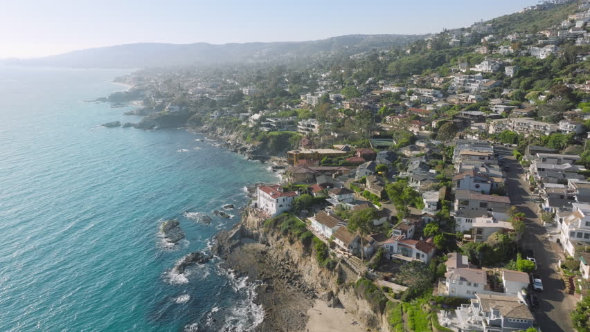 Drone flying over luxury houses and hotels on the rocks of Laguna beach, Orange County, California, USA. Picturesque landscape of private villas placed on mountain hills at Pacific Ocean, 4k footage