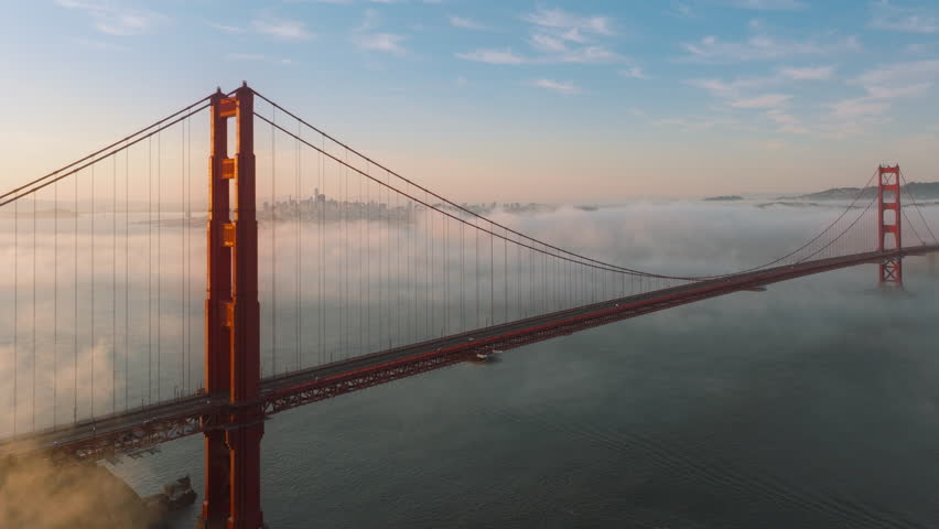 Aerial view of cars driving on Golden Gate Bridge to San Francisco, California, USA. Overhead shot of automobiles driving on route 101in morning fog. San Francisco skyline at the sunrise, 4k footage 