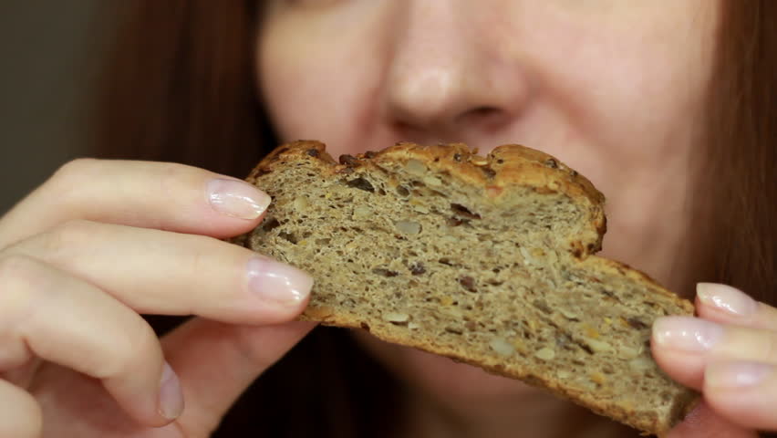 Woman eats a piece of whole grain bread. Portrait close up. Female mouth eating crusty bread. Royalty-Free Stock Footage #1111705215
