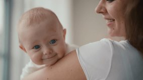 Portrait of happy family affectionate positive mom kissing baby holding in hands looking at window. Mother kisses kid at home. Motherhood, parenting, babycare, childhood, babyhood, love care concept. - Powered by Shutterstock - Get 15% off with code: PIKWIZARD15