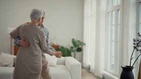 Happy smiling couple of senior wife and husband dancing together in living room at home. Gray haired man and woman. Family romantic relationship in old age concept. Elderly active people dance. - Powered by Shutterstock - Get 15% off with code: PIKWIZARD15