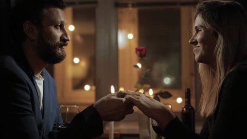 Date, Valentines Day, proposal. Man and woman hold hands during romantic dinner by candlelight and talk, have conversation Stockvideo