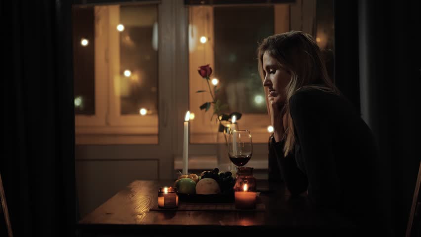 Lonely woman, failed date. Attractive sad woman sitting alone at table in beautiful romantic setting with candles, drinking wine and sometimes looking at her phone | Shutterstock HD Video #1111706875