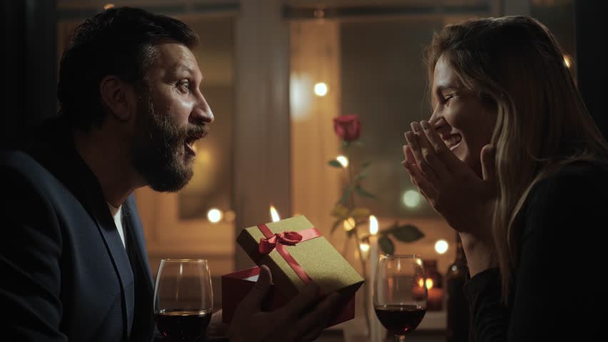 Gift, Valentines Day, wedding anniversary. Woman giving gift to man on date during romantic candlelight dinner | Shutterstock HD Video #1111706889