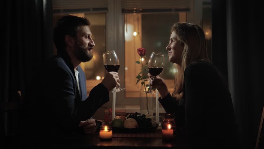 Date, Valentines Day, marriage anniversary. Romantic dinner by candlelight, man and woman sitting with glass of wine in hand and talking, chatting in romantic setting | Shutterstock HD Video #1111706893