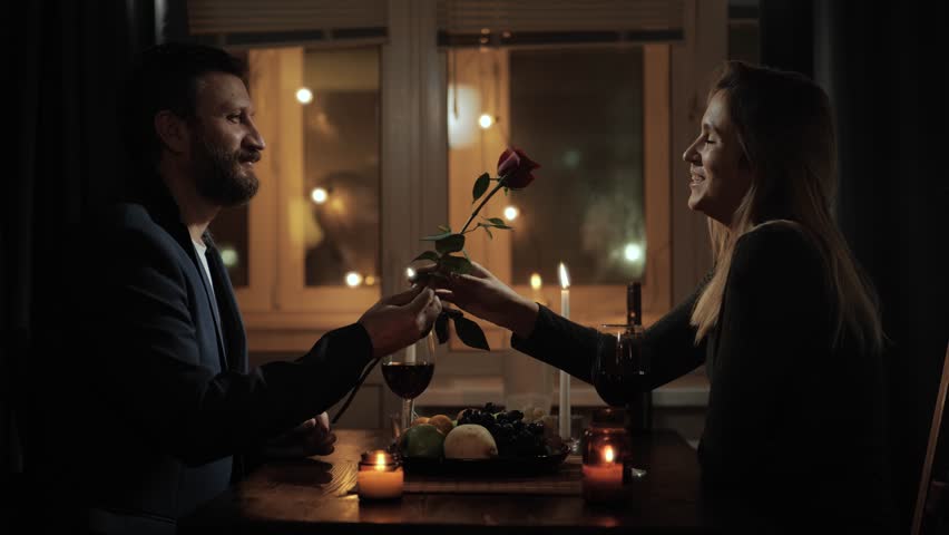 Date, Valentines Day, first date. Man gives one rose to woman during romantic candlelit dinner in restaurant or at home | Shutterstock HD Video #1111706899