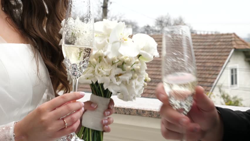 The newlyweds stand on the balcony and toast with glasses of white wine. | Shutterstock HD Video #1111707541