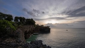 Time lapse sunset on the Honeymoon Beach is a popular tourist destination located on the Bali island, Indonesia. Ocean beach sunrise with color sky clouds and sun rays over sea waves 4K video