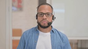 Smiling African Man with Headset Looking at Camera in Call Center