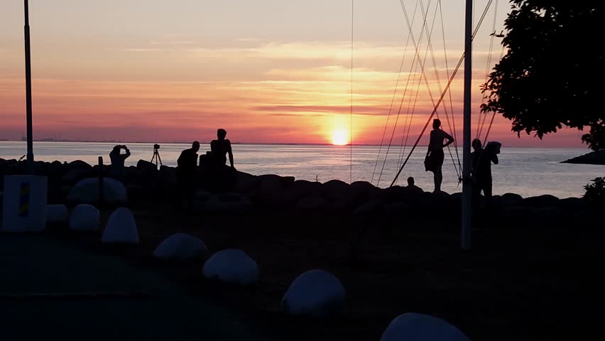 Residents of Malmo watching the sunset. Silhouette of Copenhagen in the distanceHigh quality 4k footage