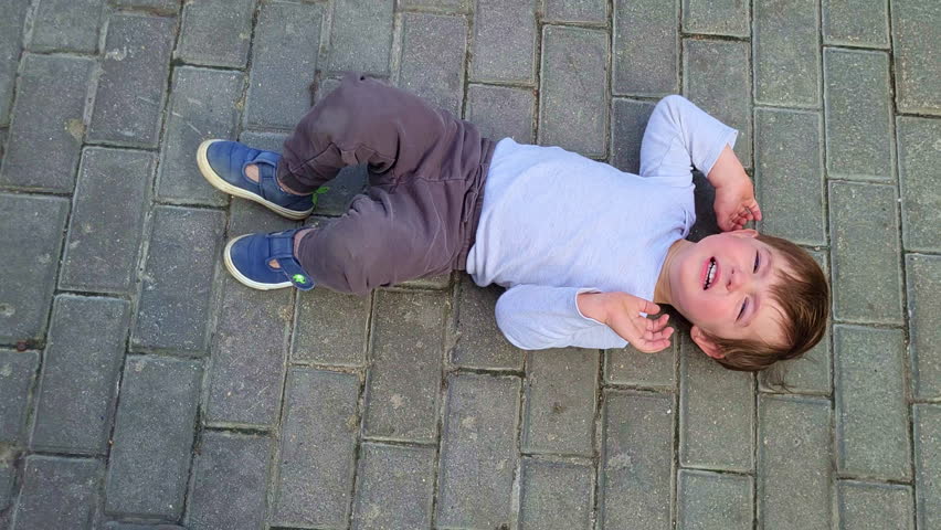 A capricious child lies on the ground in cry refusing to go. Baby aged two years (two-year-old boy) Royalty-Free Stock Footage #1111713063