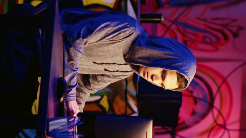 Vertical video New member in hacking group asking mentor for help in underground hideout. Script kiddie requesting assistance with virus development from master hacker in graffiti painted base