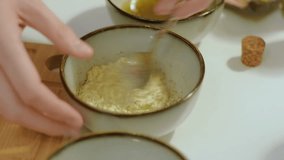 Woman preparing a marinade for cooking meat or vegetarian recipes on the white table. Spices, garlic, soy souce, oil, salt, herbs, mayonnaise. Cooking food concept. High quality FullHD footage