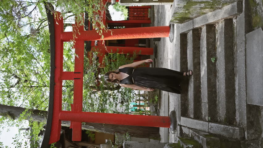 Cheerful, beautiful, hispanic woman with glasses walks confidently towards the camera, her glowing smile lighting up the historic kyoto temple in the background. joyful travel in japan!