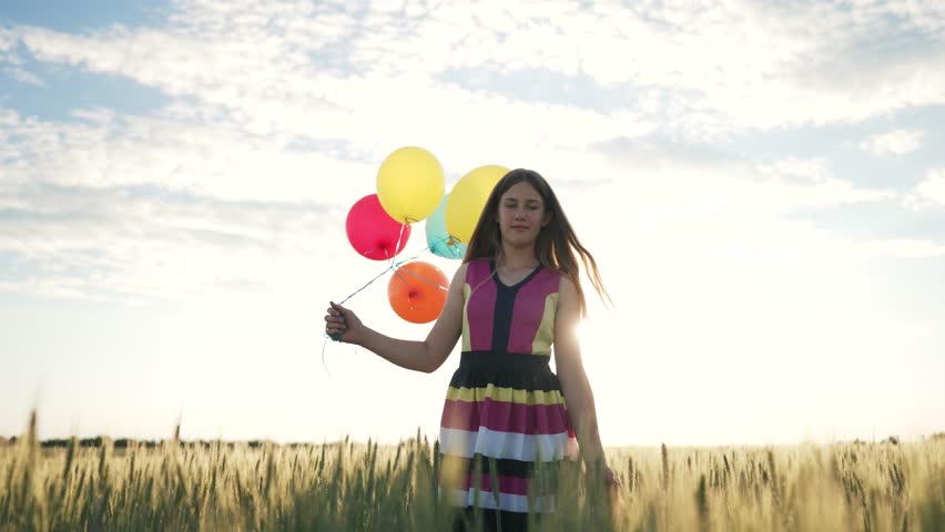 Happy family concept. Child with balloons has fun playing in field in spring. Freedom and childhood dream. Girl run with balloons in sun. Child in wheat field at sunset in summer. Girl playing in park | Shutterstock HD Video #1111723451