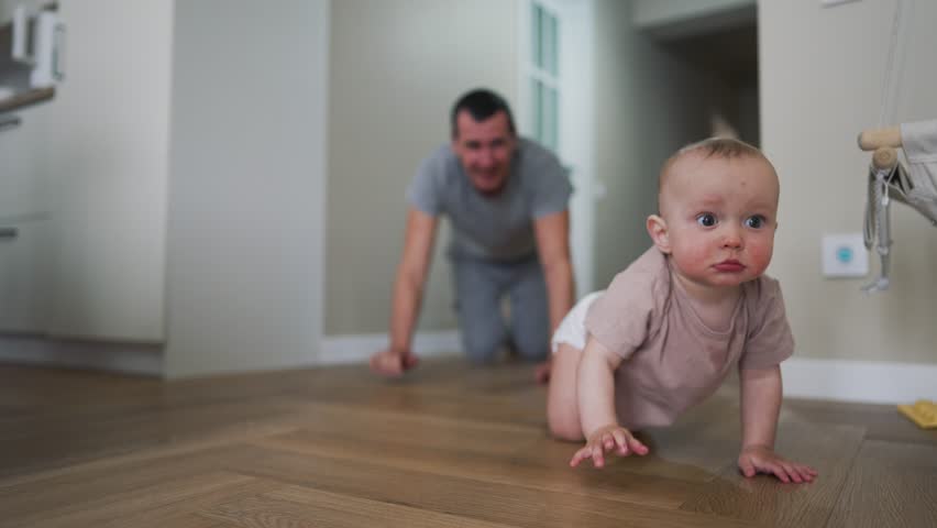Happy family. Baby crawls on floor with his father. Boy smiles and crawls on floor of house. Dad plays with his son at home. Home kindergarten.Father's day in kindergarten.Happy baby crawling on floor Royalty-Free Stock Footage #1111723473