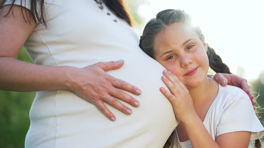 Happy family. Daughter hugs belly of mother pregnant woman. Waiting for baby son. Pregnant woman in park in nature with her daughter hugs her belly.Pregnant woman concept of dream baby and family love | Shutterstock HD Video #1111723505