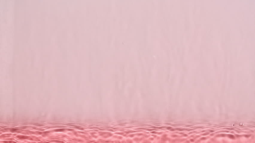 Pure pink water with reflections sunlight in slow motion. Water surface texture. Sun and shadows. Motion clean swimming pool ripples and wave. High quality 4k footage