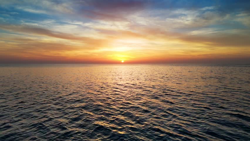Epic sunset over the sea or ocean. Flying above water surface at red sunset sky. Sun reflect in the sea, aerial drone shot
