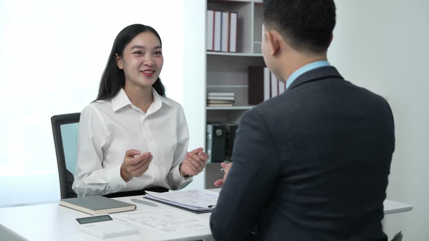 A successful businessman interviews a smart young woman for work in a respectful, professional atmosphere with a busy conversation. Two sides in modern office Royalty-Free Stock Footage #1111732339