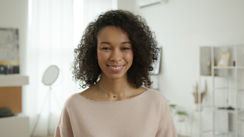 Confident smiling young adult bi racial woman standing at modern home. Portrait happy millennial casual professional lady with white teeth looking at camera. Pretty face woman of color posing indoors Royalty-Free Stock Footage #1111734851