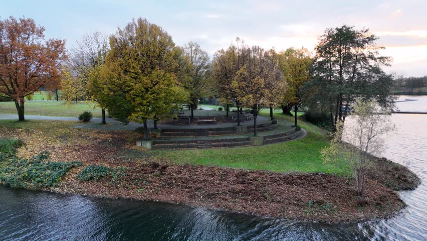 drone footage of a relaxing area under the autumn trees at a lake