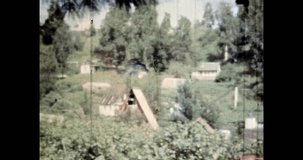 Green village in sunny summer. Rural houses in green trees landscape. Countryside buildings cabins in fresh nature. Holidays in country house. 4k vintage footage of cinema archival film. 1980s archive