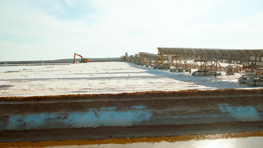 Natural salt production fields or salt flats in Marismas del Odiel, Huelva, Andalucia, Spain, where evaporation pools turn seawater into white gold, where salt is harvested using machinery
