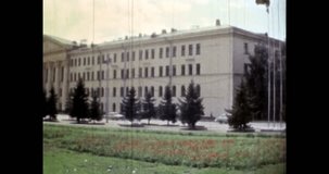 Administrative building view in summer city landscape. Wide footage. Cars moving by road. Government architecture landmark in cityscape. Retro archival film. 1980s Russia street. Vintage archive