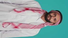 Vertical video Islamic guy turns to Allah for hope trusting in sacred meditation over blue background. Middle eastern person honoring God through holy ritual, showing devotion and praying.