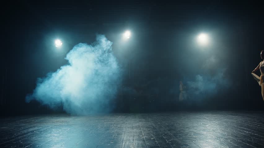 Graceful ballerina in flowing dress high jump in dance hall. Silhouette of a slender ballerina in spotlight and stage smoke