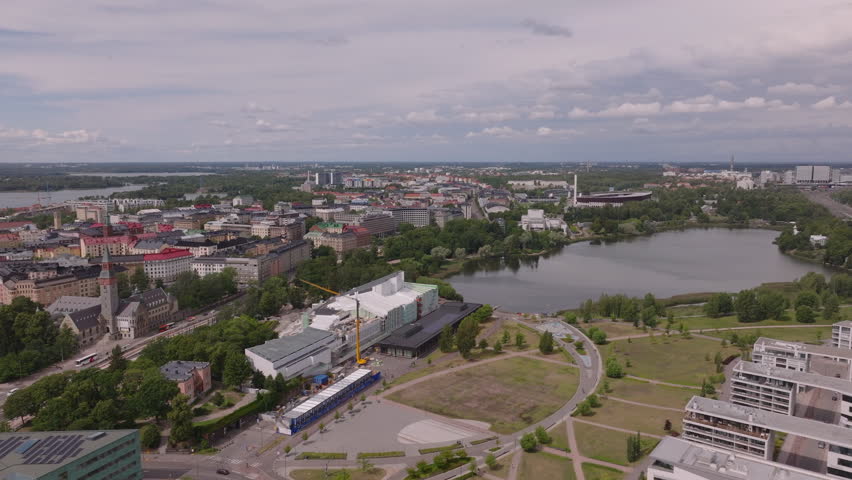 Forwards fly above green park and Finlandia Hall congress and event venue on lake bank. Helsinki, Finland