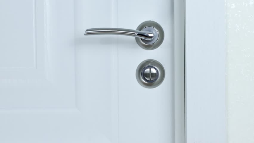 Close-up image of a frustrated girl's hand struggling to open a white door. The girl's hand is shown in detail, conveying a sense of struggle and frustration against the white door. Royalty-Free Stock Footage #1111754485