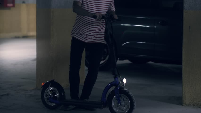 Man starts off on electric scooter in underground parking lot, using modern electric vehicles instead of gasoline transport | Shutterstock HD Video #1111755917