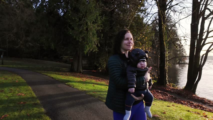 Mother Holding, Walking with Cute Baby Boy. Pier on Sunny Fall Day. Park, West Coast, Belcarra. Vancouver, British Columbia Canada. High quality 4k footage