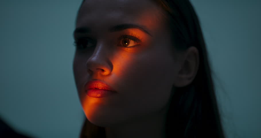 Beautiful unreal portrait fashion pretty girl with color lighting filters. Beauty girl face close up. Closeup woman with copy space standing isolated in front of light orange color.