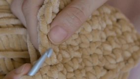Vertical video. Close-up of woman knitting with beige wool yarn, showcasing intricate knitting skills. Detailed view of knitting process with beige yarn. Ideal for knitting tutorials and craft content