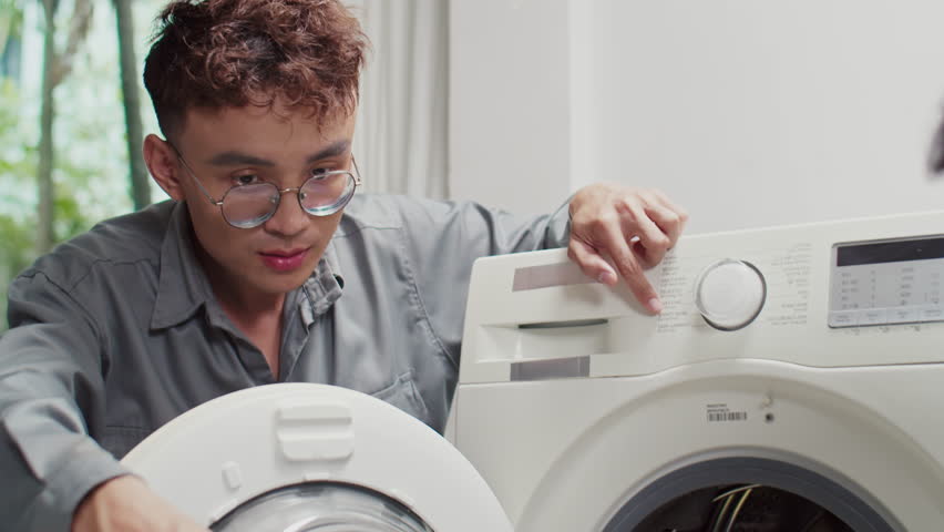 Medium close up of male plumbers discussing how to fix broken washing machine indoors