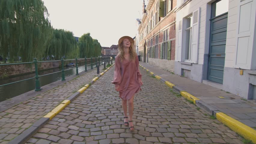 charming blonde woman walks down the city street, smiling, light, and happy