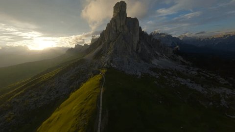 Стоковое видео: First person Drone flying over mountain peak. Drone view over mountains in Dolomites, Italy. FPV Drone mountain surf through clouds. Golden Sunset breathtaking views of Italian Dolomites