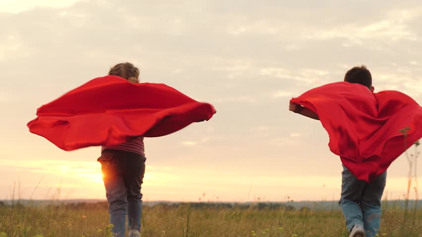 Children races on field in capes resembling superheroes. Children wearing capes dashes across field with energy at dusk. Children team playing superheroes runs on field while capes flutter in wind | Shutterstock HD Video #1111770133