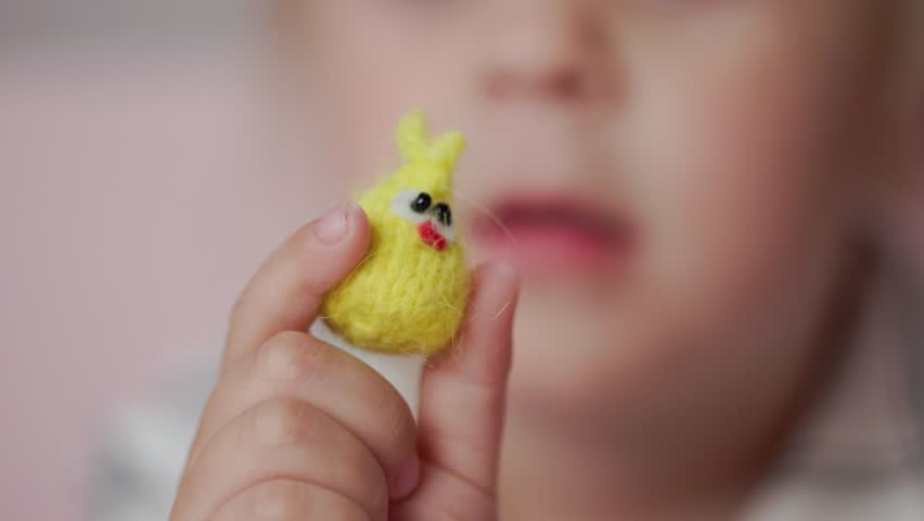 Girl child plays with small knitted animal toys in a room at home